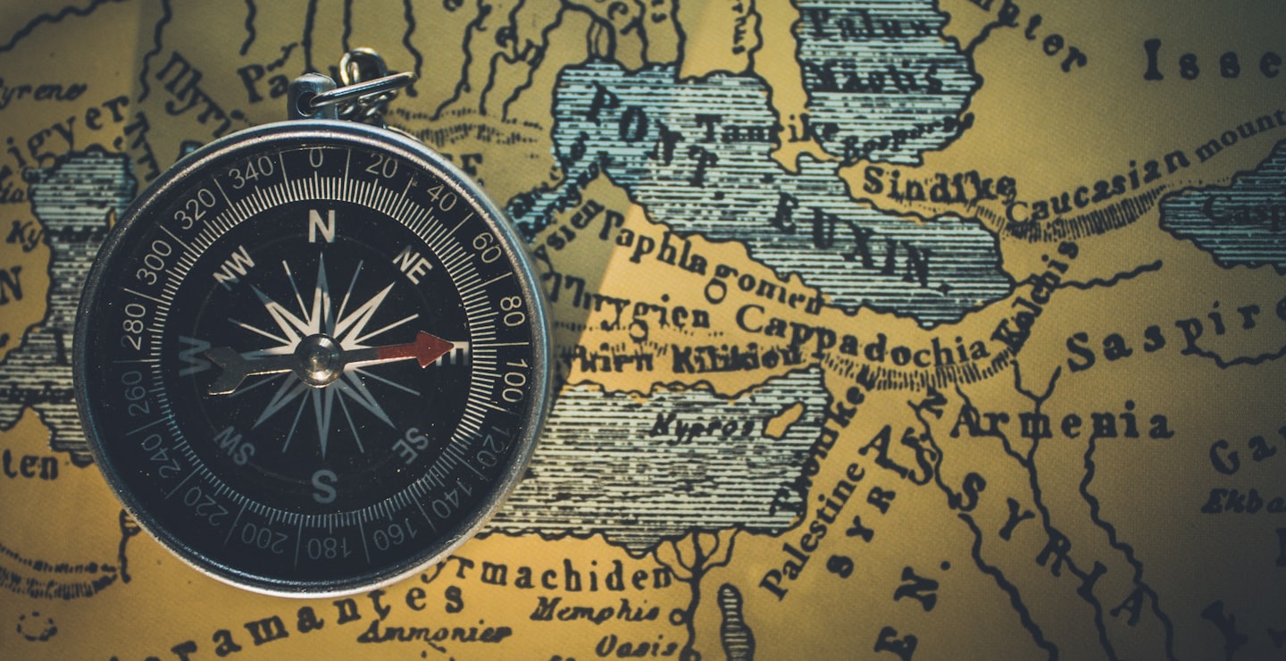 Vintage compass resting on a detailed antique world map.